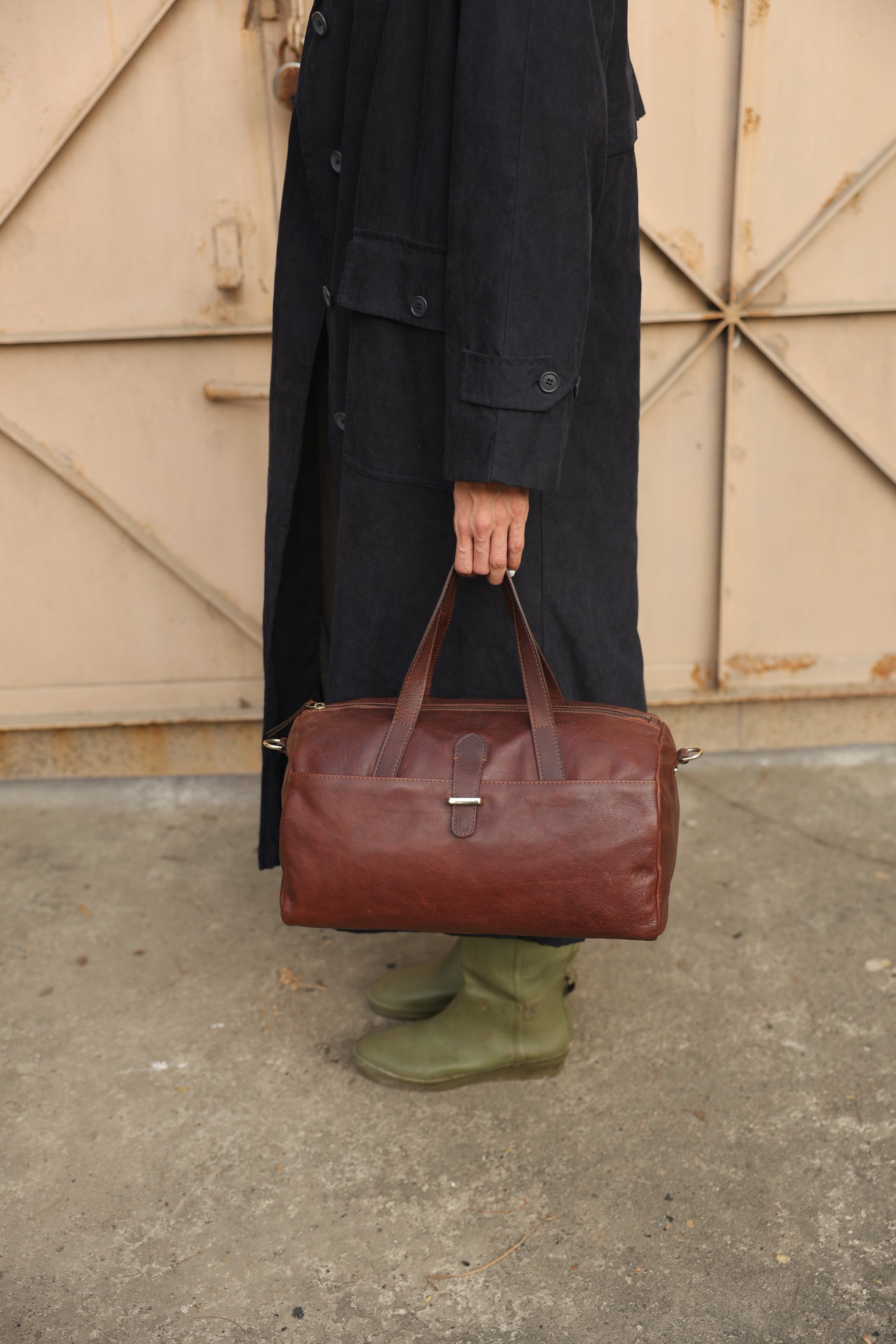 Artisan holding handcrafted brown leather weekender bag
